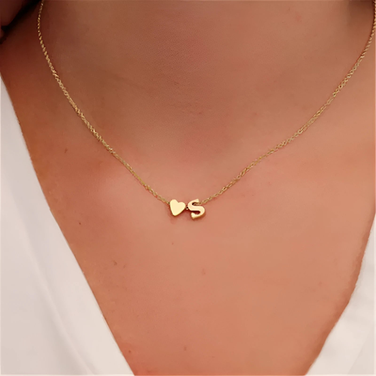 Golden peach heart shaped alloy necklace pendant with a letter design on a white background.