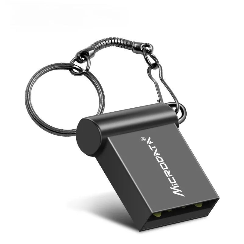 Silver car-shaped metal USB flash drive on a chain, shown next to a laptop.