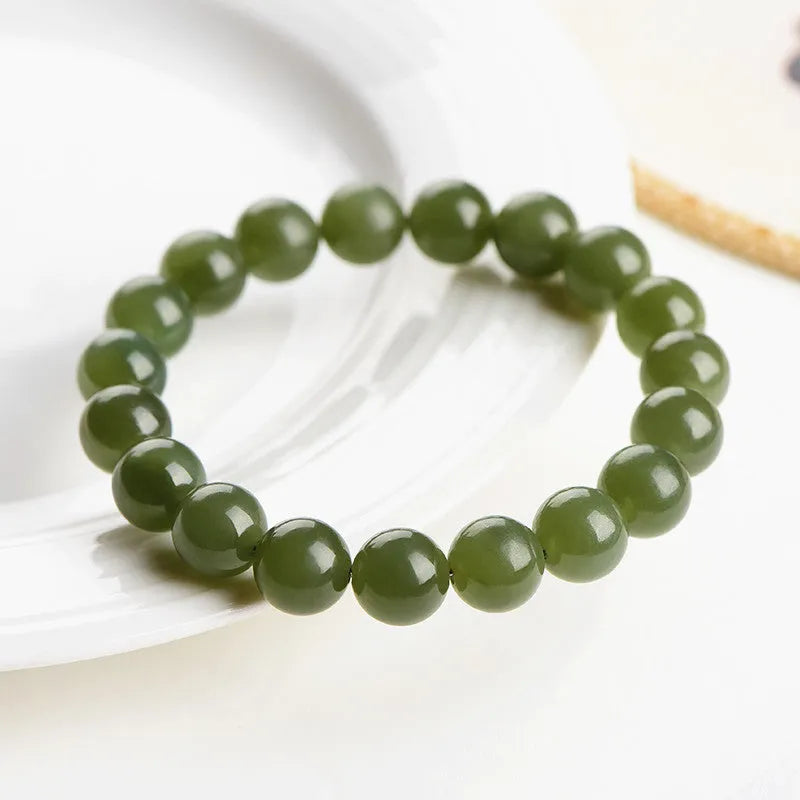 A polished Hetian Jade ball bracelet in a clear water colour on a wrist, showing spherical beads.