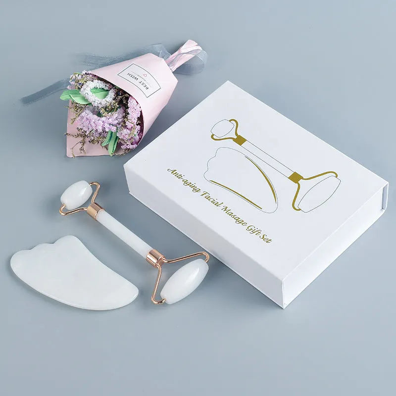 Natural white jade double-headed facial roller and gua sha scraping board set on a plain background.
