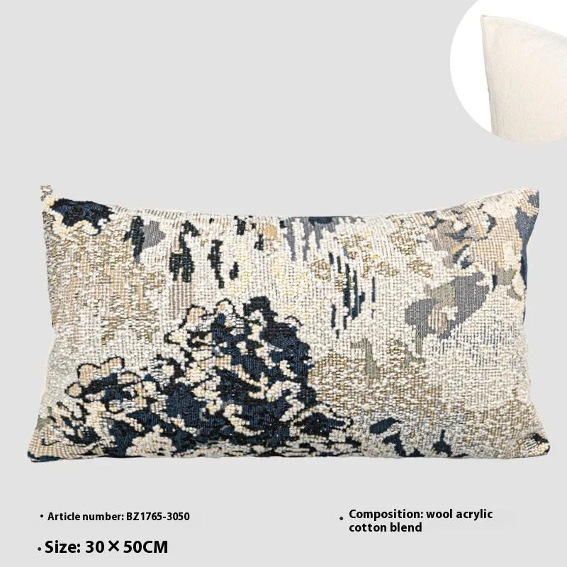 Blue decorative pillow with abstract flower pattern in 50x50cm square size on a grey sofa.