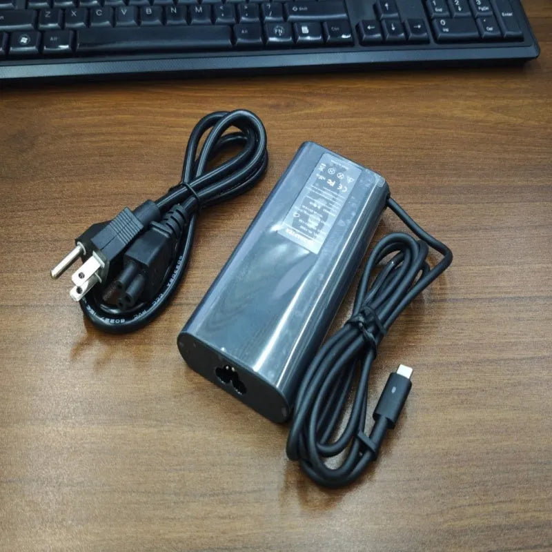 Black 65W USB-C laptop power adapter with set of international plug cords.