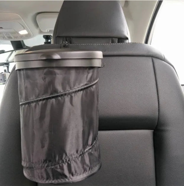 Black cylindrical foldable car trash bin 16x20.5cm with adjustable strap for vehicle cleaning and storage on a seat