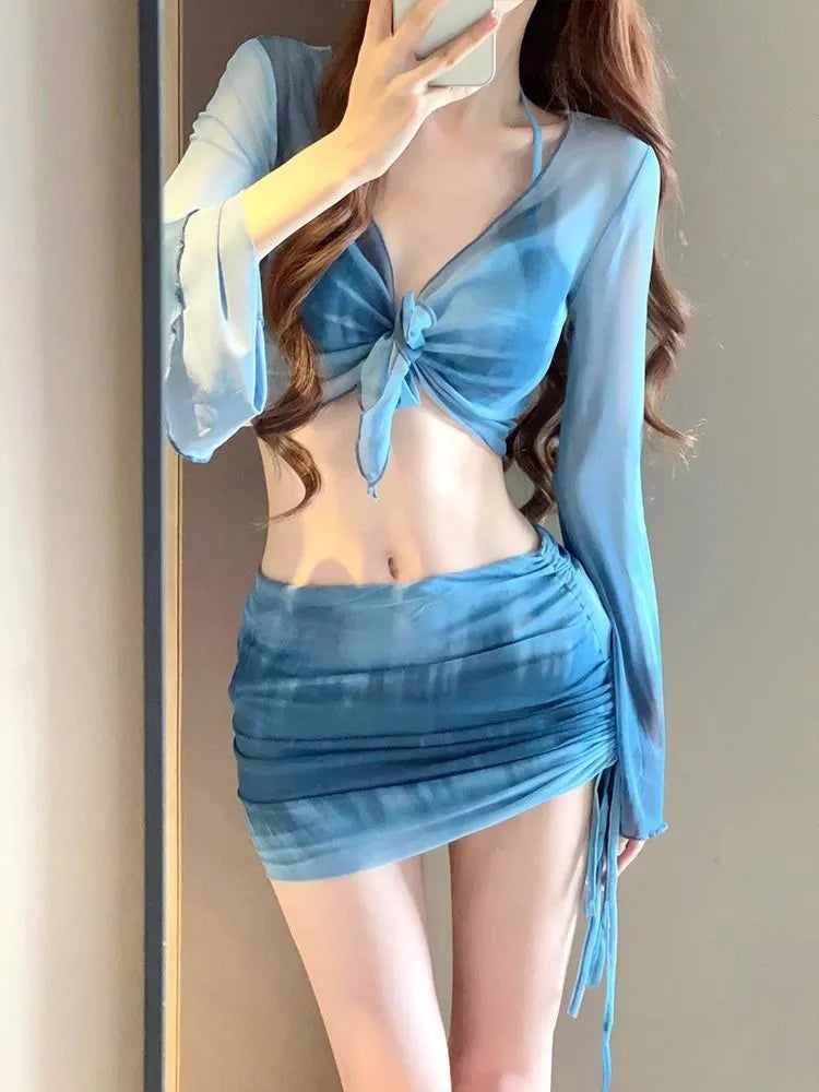 Women's blue four-piece bikini swimsuit set with high-waisted briefs, shirt, and skirt laid flat.