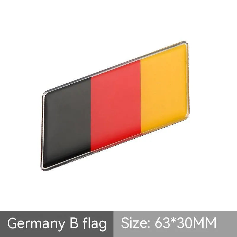 Aluminium parallelogram car sticker showing a national flag design, measuring 6.3 by 3 centimetres.