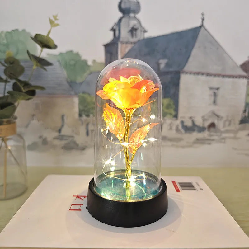 Small decorative night lamp with glass cover, plastic flower, and black base on a pink box.