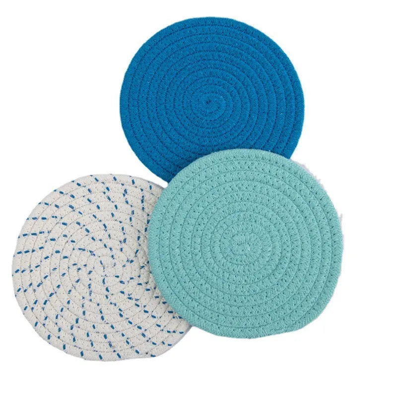 Set of three round grey cotton cord coasters on a wooden table.