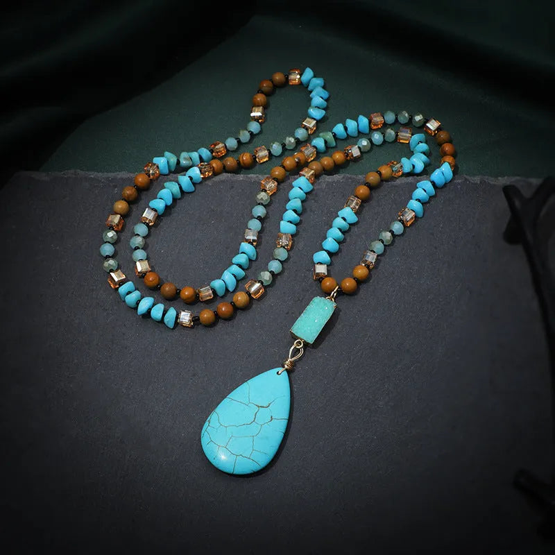 Close-up of a large turquoise blue heart-shaped water drop pendant necklace on a ball bead chain.