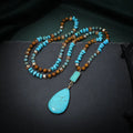 Close-up of a large turquoise blue heart-shaped water drop pendant necklace on a ball bead chain.