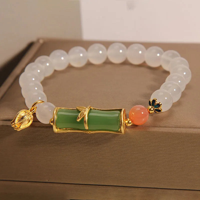 Women's white agate and jade bamboo joint beaded bracelet on a wrist.