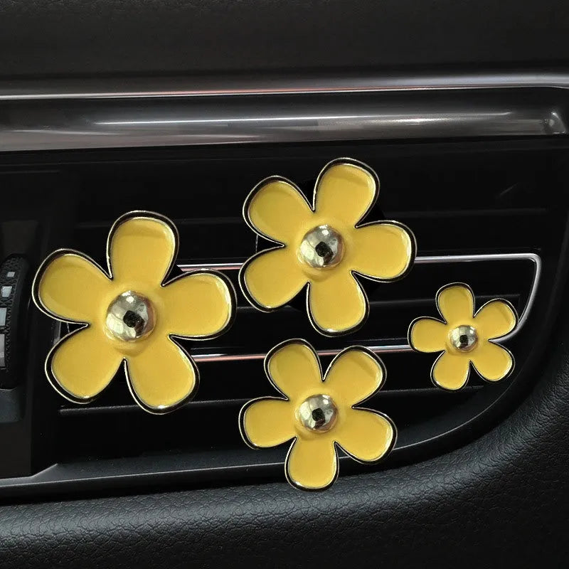 Set of four metal car air conditioning flower aromatherapy clips in assorted colours on white background
