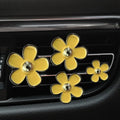 Set of four metal car air conditioning flower aromatherapy clips in assorted colours on white background