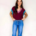 Burgundy loose V-neck short sleeve sweater with contrast trim detail on the neckline and cuffed sleeves.