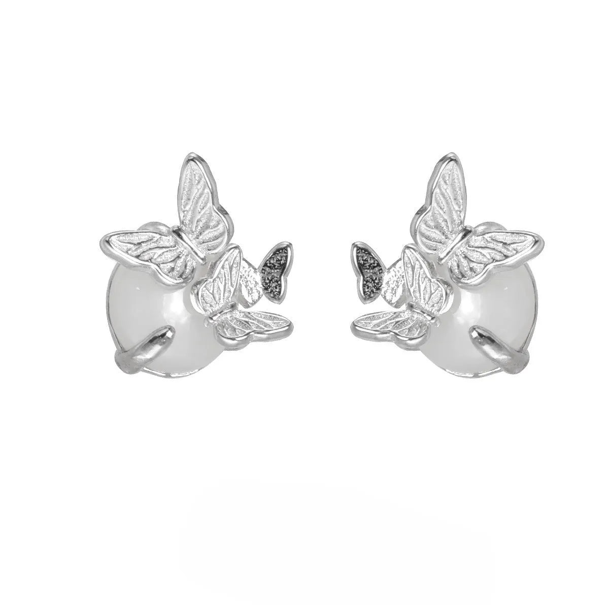 Close-up of a pair of silver butterfly stud earrings with a gold-toned finish.