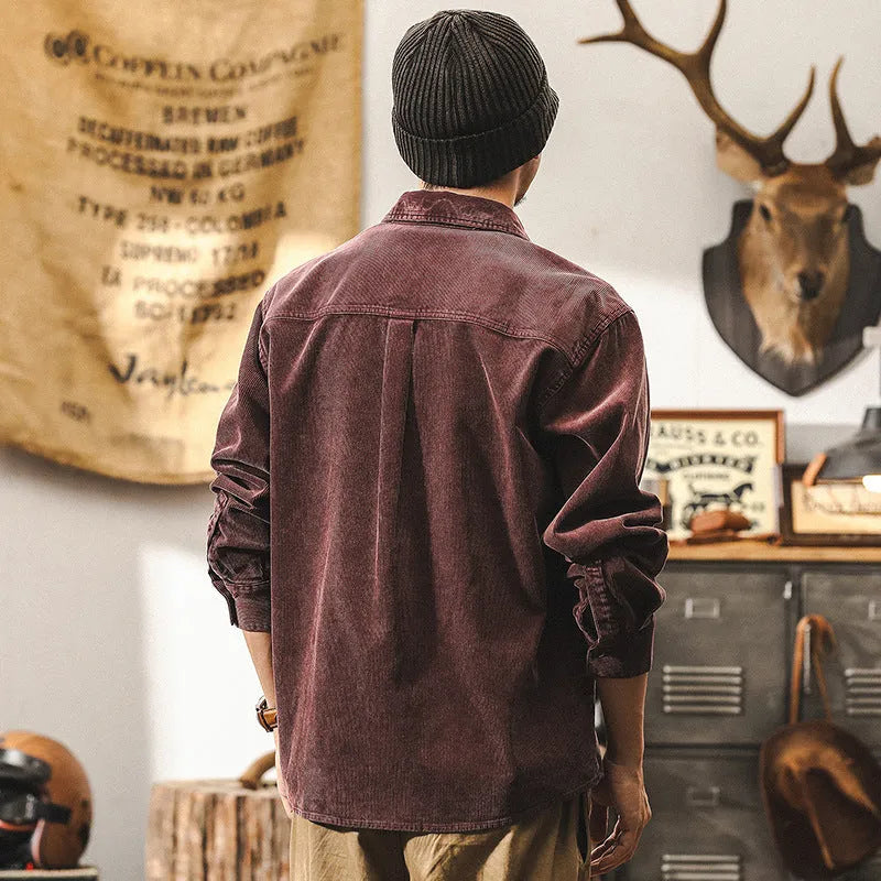 Man wearing a red loose-fit corduroy shirt jacket, showing textured fabric and button-front design.