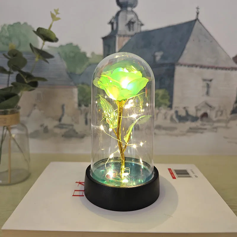 Small decorative night lamp with glass cover, plastic flower, and black base on a pink box.