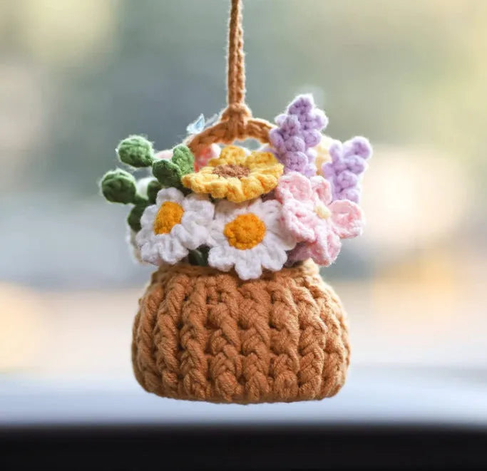 Green and white knitted wool car plant decoration with macramé texture and a white hanging rope.