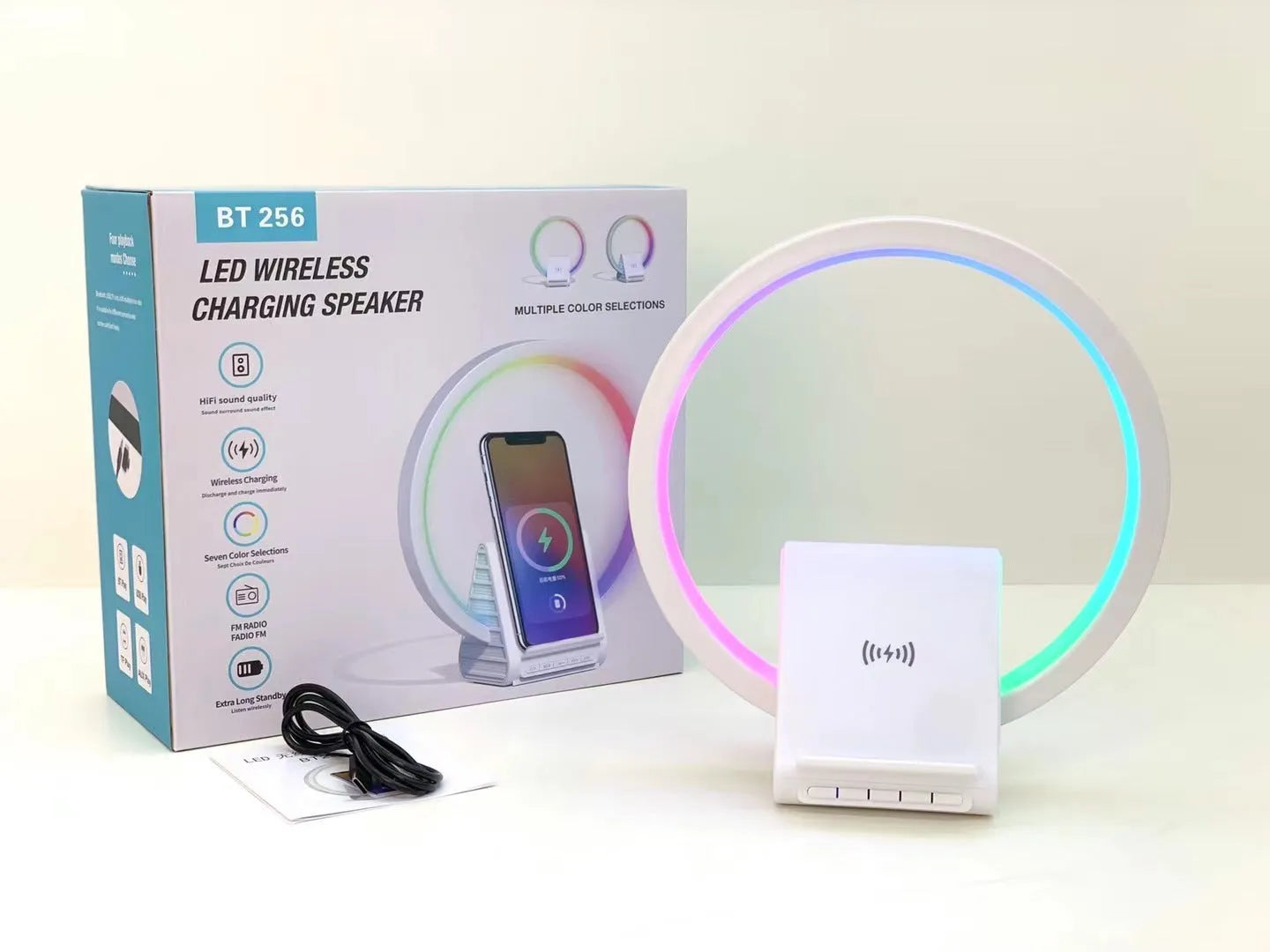 White smart Bluetooth speaker with wireless charging pad and ambient lighting on desktop