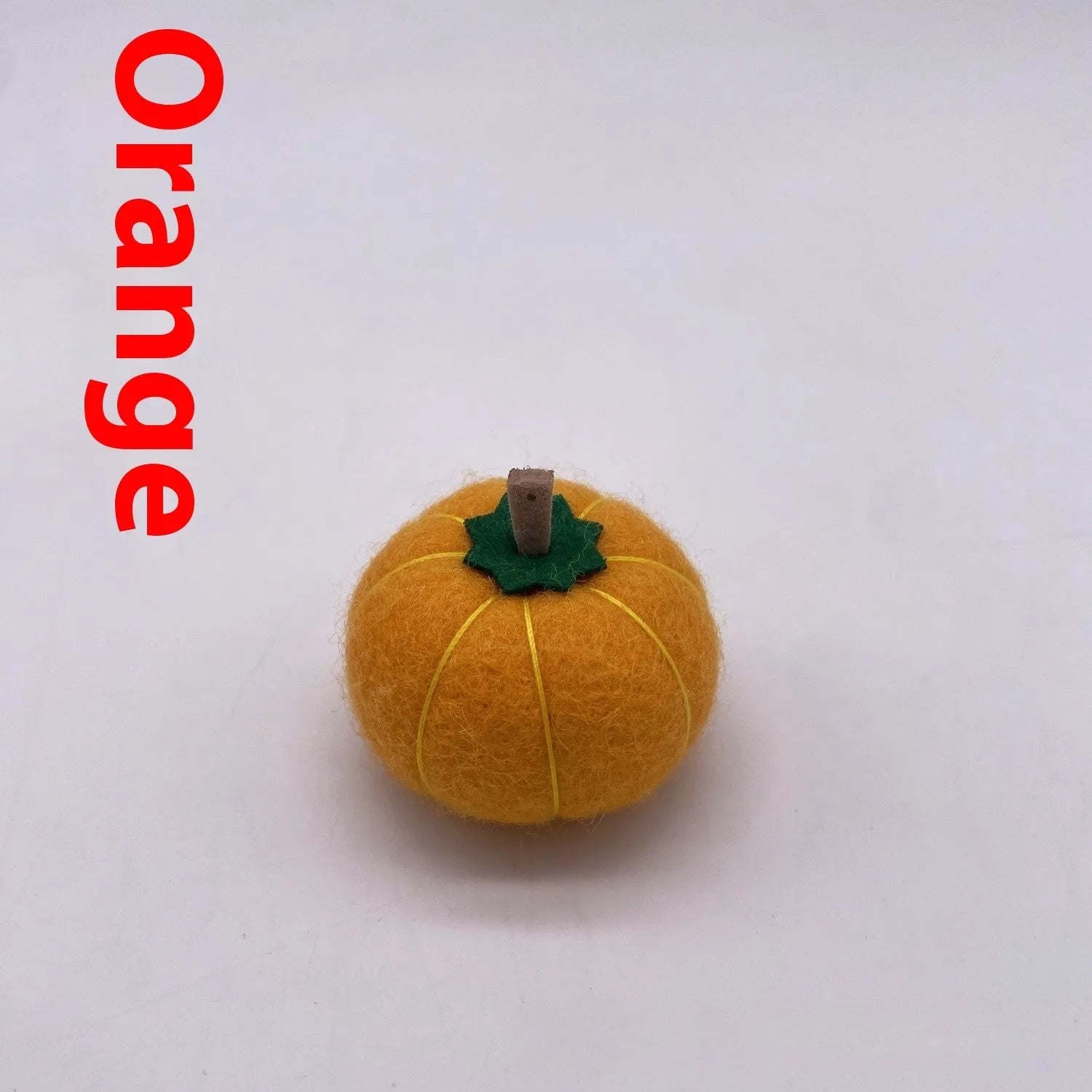 Wool felt pumpkin-shaped doll decorations in autumn colours on a neutral background