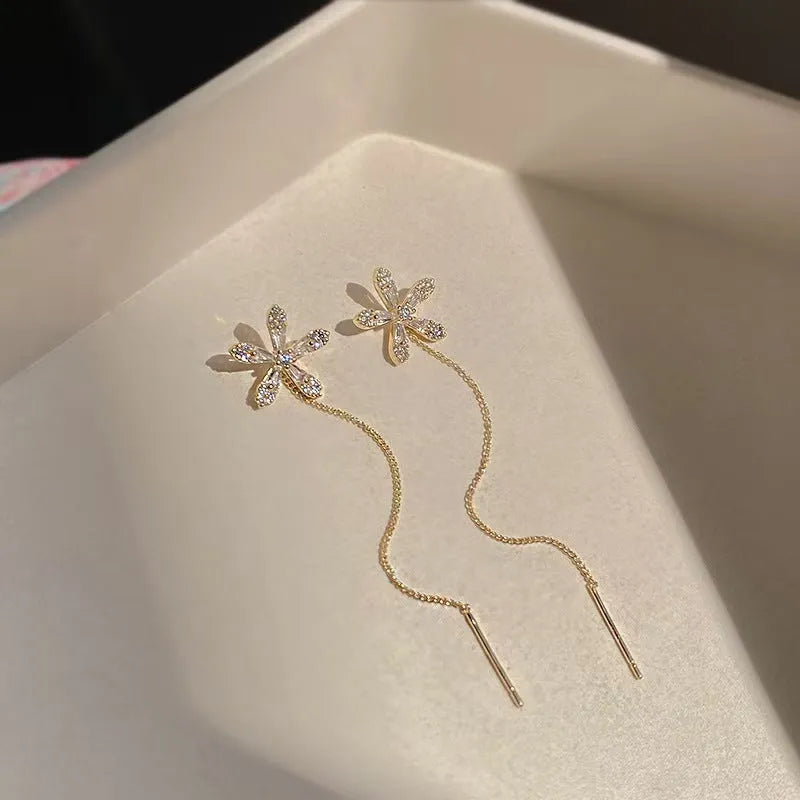 Long gold drop earrings for women with metal construction and secure fastening on white background