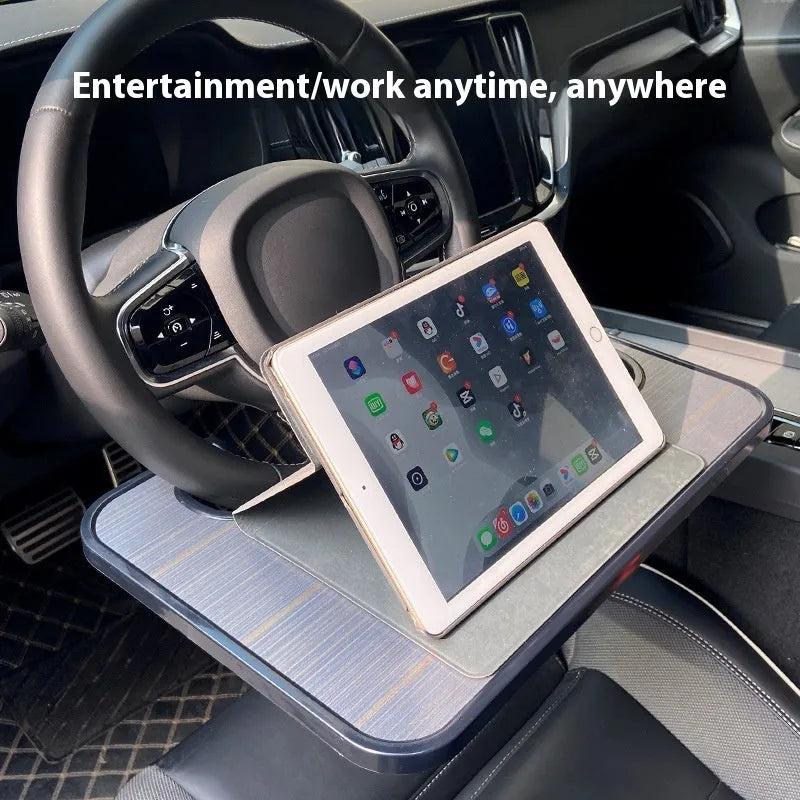Black foldable ABS plastic tray positioned on a car steering wheel, shown with a laptop and foldable cup holder.