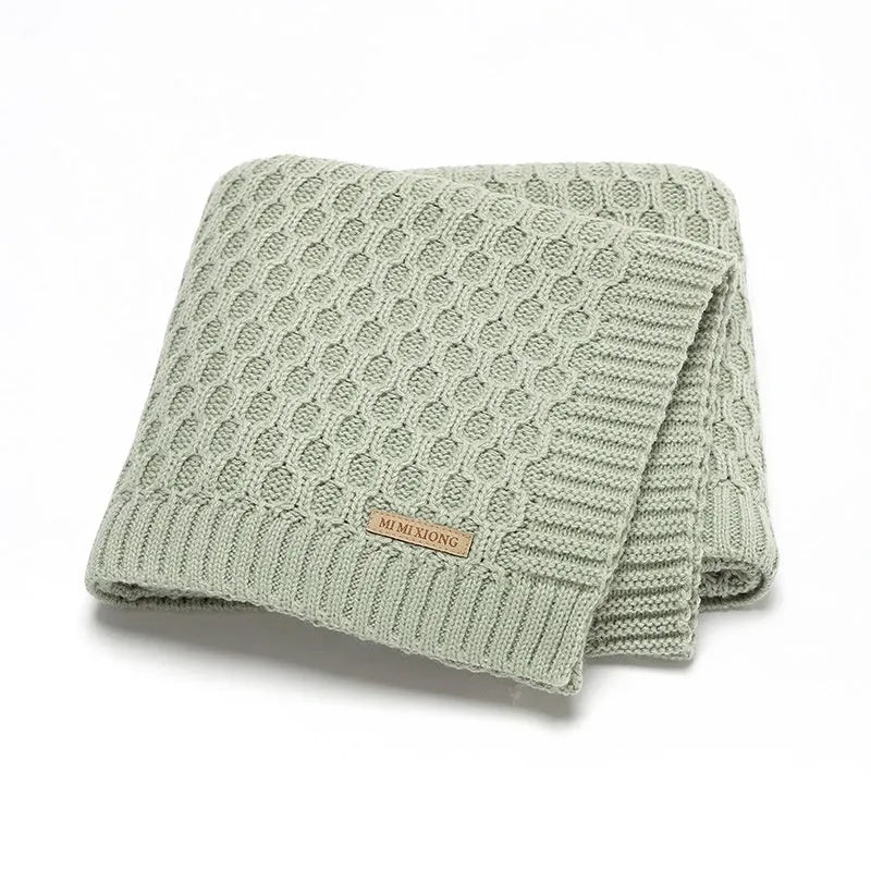 Solid-colour infant blanket with raised three-dimensional lines, shown in a light green colour.