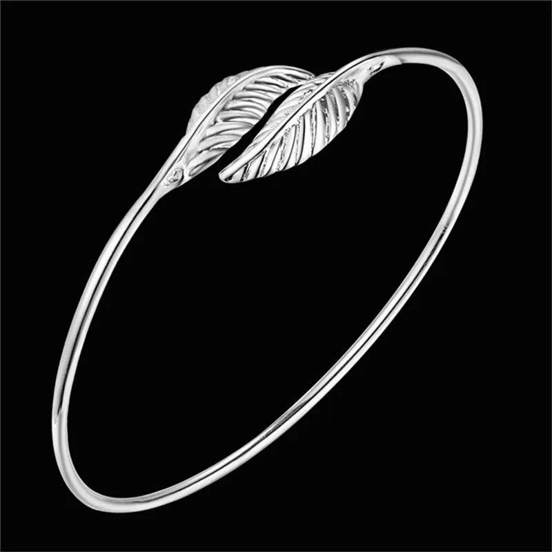 Silver metal bangle bracelet with open cuff design, 6.3cm diameter, on white background