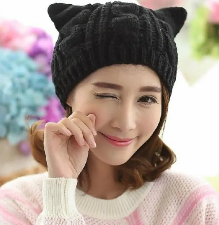Hand made 3D knitted cat ear beanie in wool, shown in multiple colour options including red, black and beige.