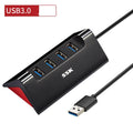 Black USB expansion dock with 4 ports and a Micro USB power input on a desk.
