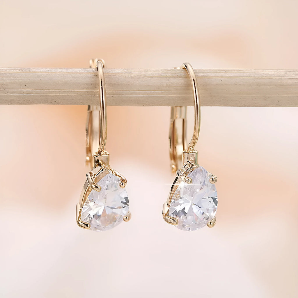 A pair of women's drop-shaped fashion earrings in gold or platinum finish with a platinum-inlaid gemstone.