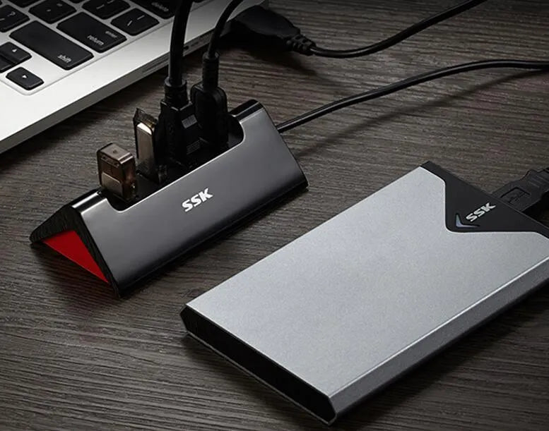 Black USB expansion dock with 4 ports and a Micro USB power input on a desk.