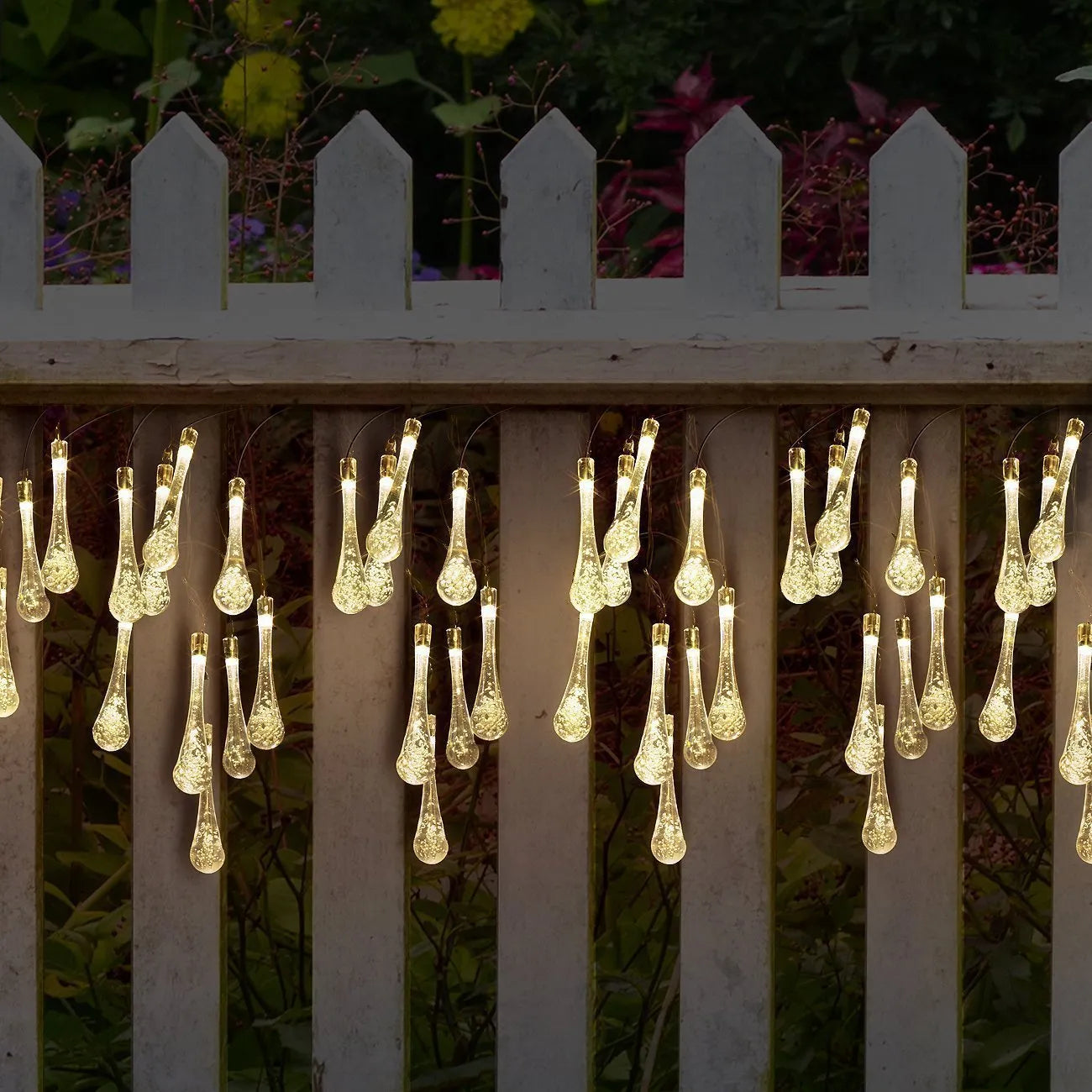Solar-powered outdoor string lights with water drop shaped pendants on a 6.5 metre cable, shown with solar panel and ground spike.