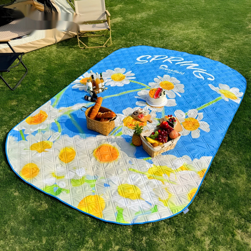 Waterproof outdoor picnic mat in a seasonal colour, shown unrolled on grass.