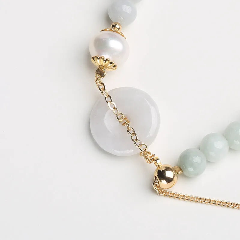 Jade green bracelet with peace buckle fastener and round pearl charms on wrist