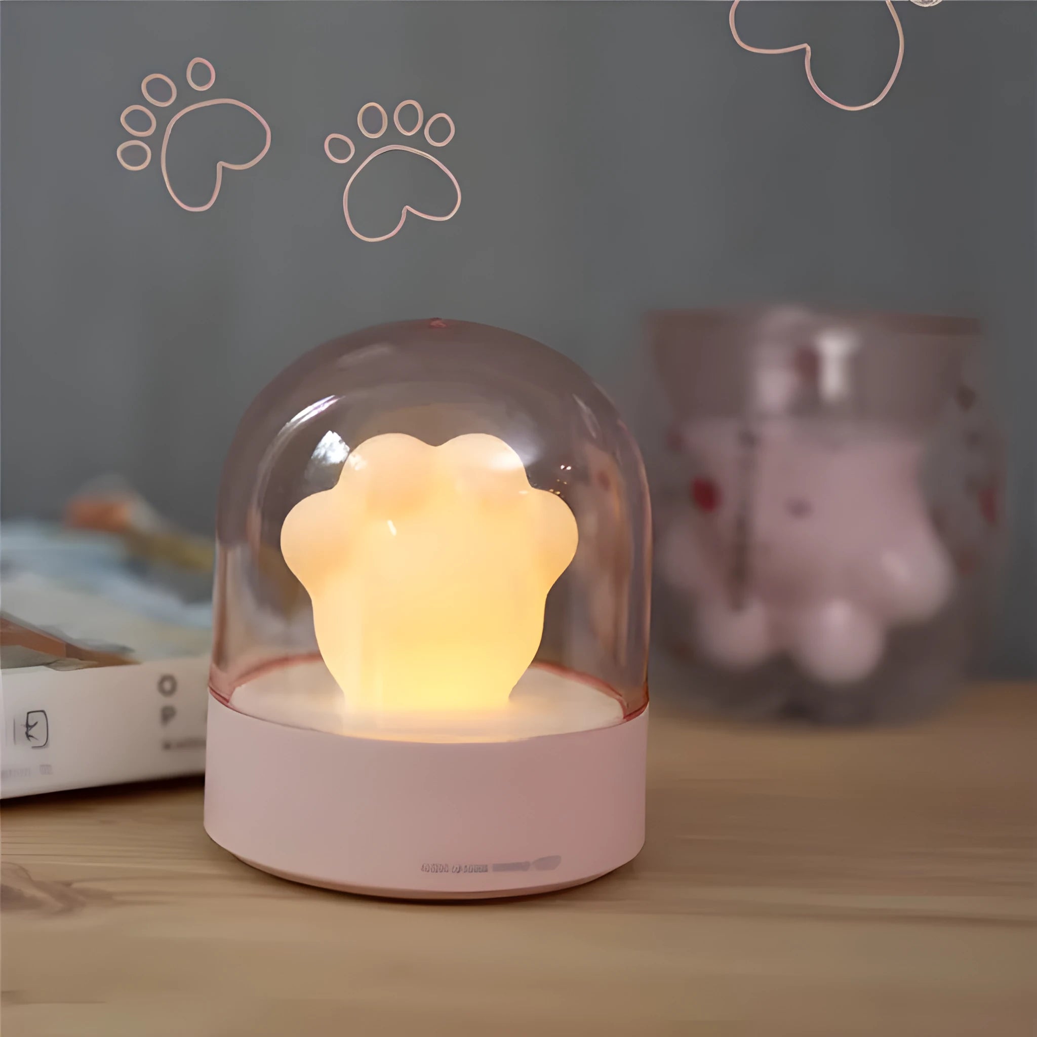 Grey or pink cat paw shaped USB rechargeable night light and music box on a desktop.