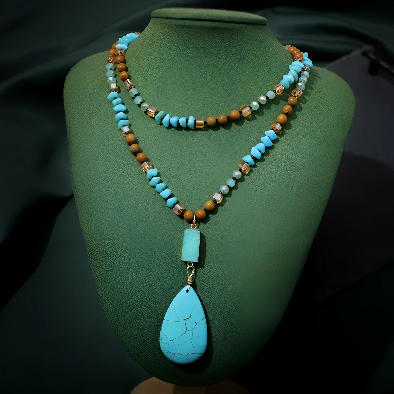 Close-up of a large turquoise blue heart-shaped water drop pendant necklace on a ball bead chain.