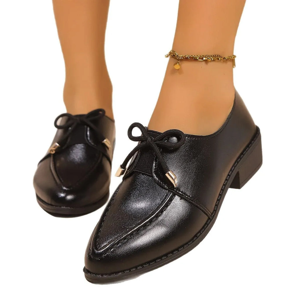 Women's beige loafers with a large decorative bow, showcasing rounded toe and slip-on design.