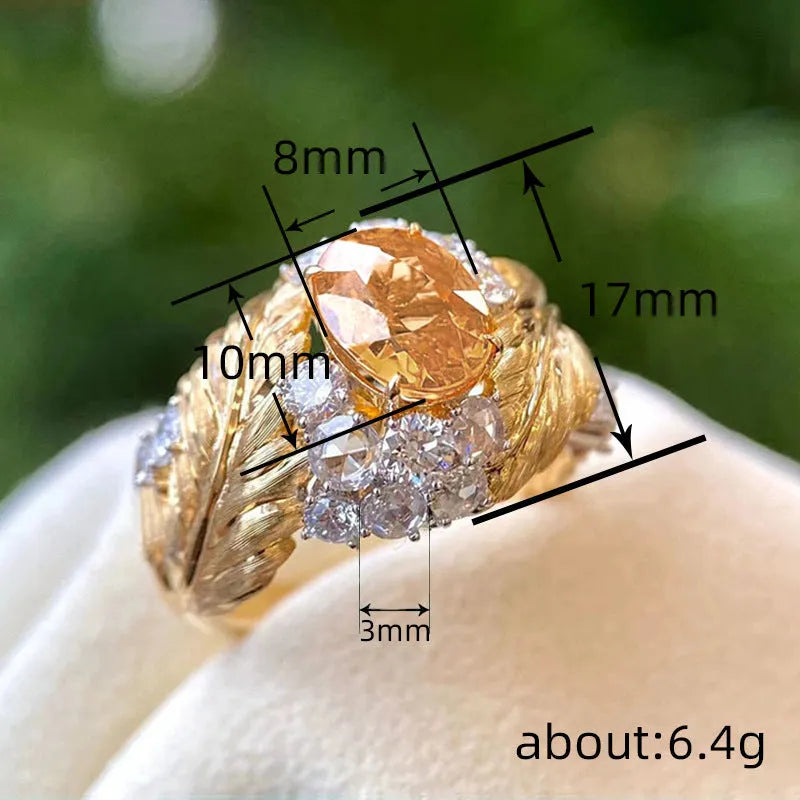 Gold-toned copper ring with embossed feather pattern and a central yellow zircon stone on a geometric band.