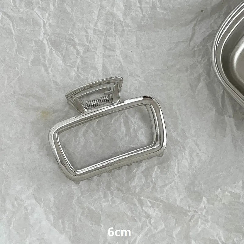 Assorted silver metal hair claws and barrettes including wave, knot, bow, and pearl designs on a white background.