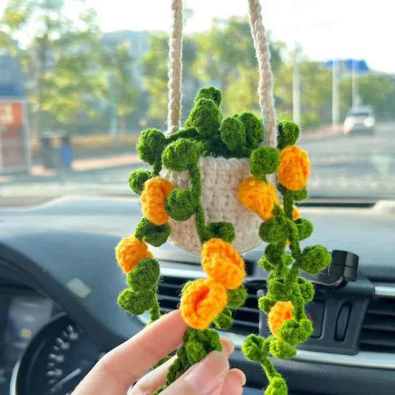 Green and white knitted wool car plant decoration with macramé texture and a white hanging rope.
