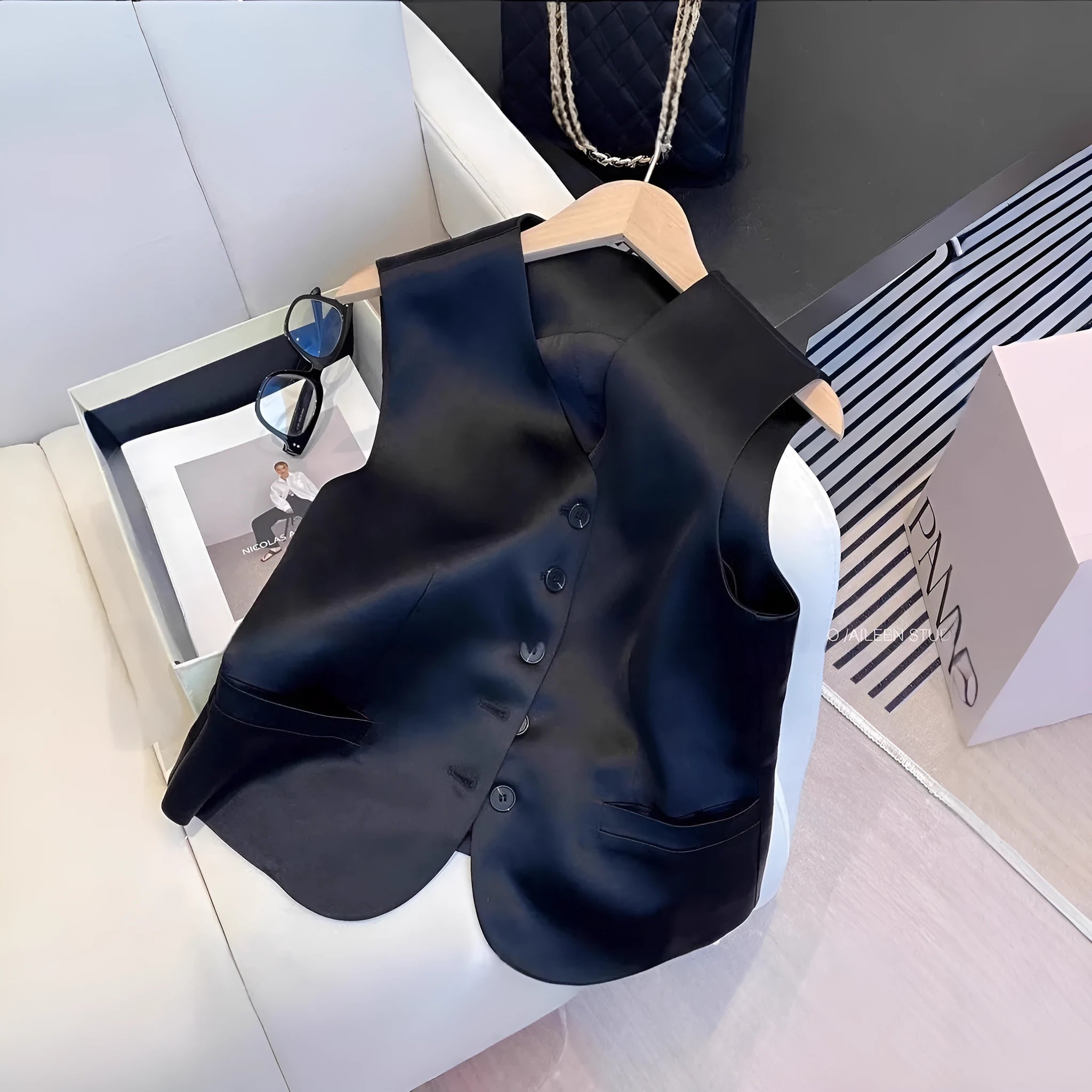 Black satin ladies sleeveless vest on a hanger, showing loose fit and splicing detail.