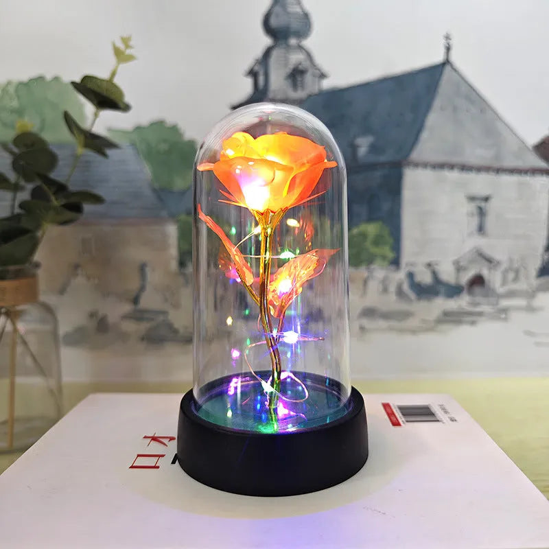Small decorative night lamp with glass cover, plastic flower, and black base on a pink box.