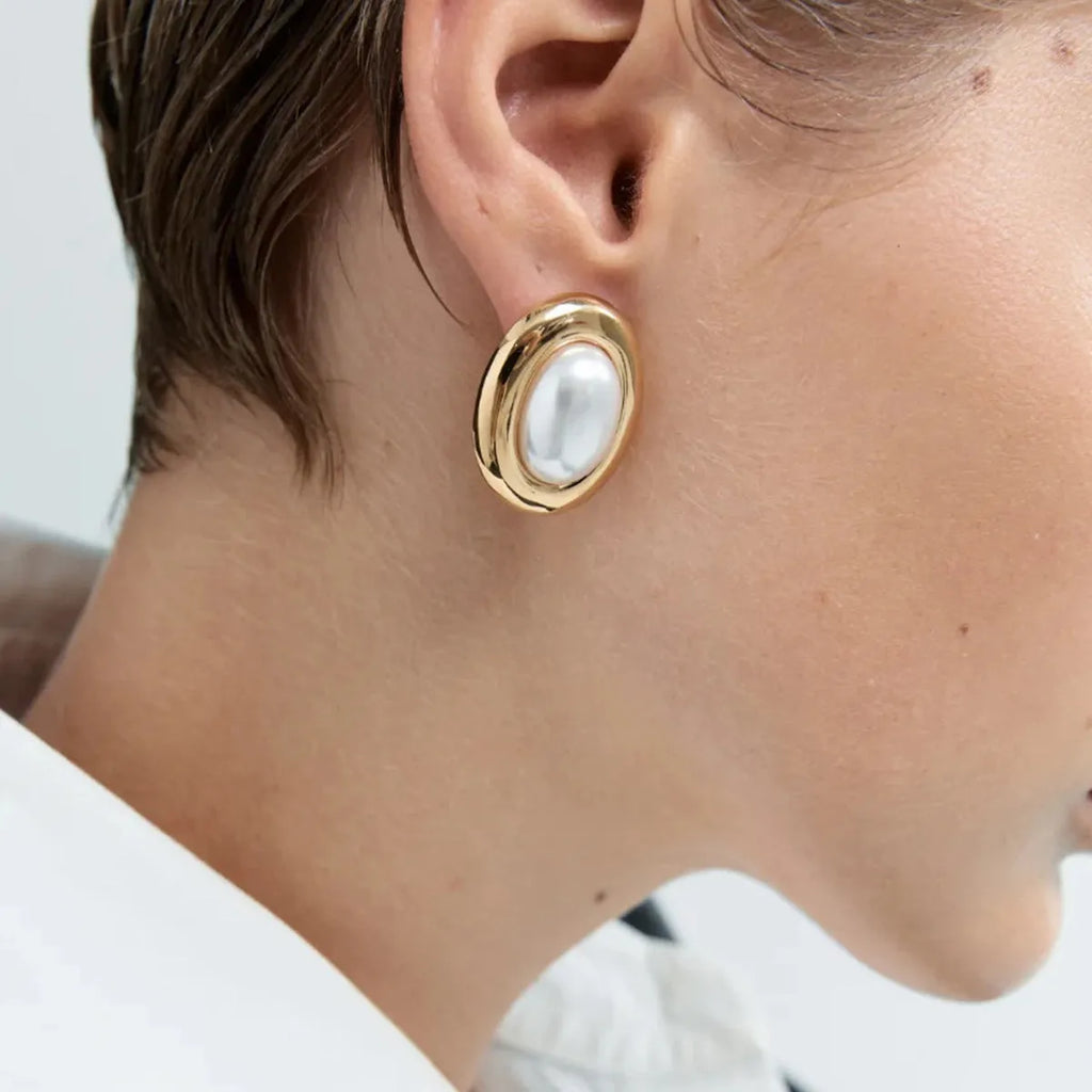 Close-up of women's stainless steel vintage pearl stud earrings with a silver-toned electroplated finish.