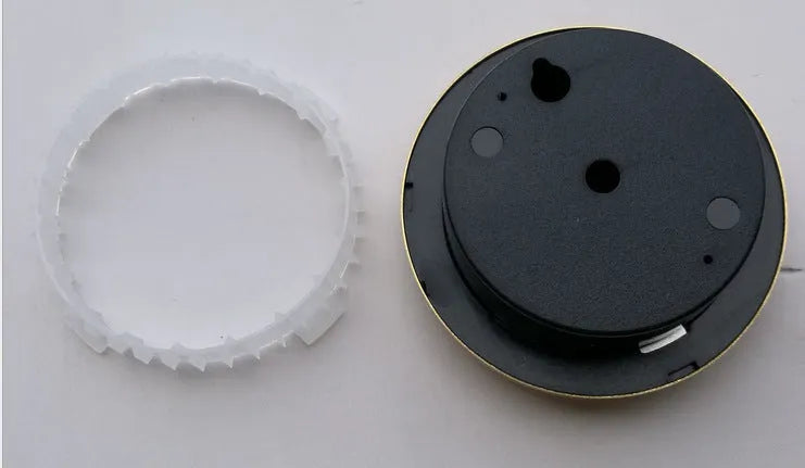 Analogue thermometer and hygrometer with aluminium dial on a white wall.