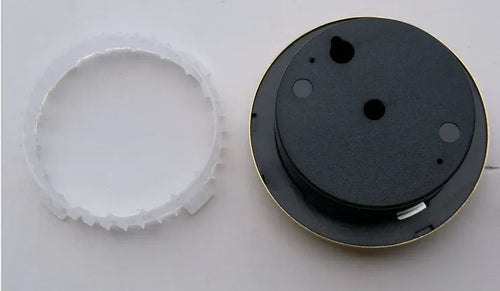 Analogue thermometer and hygrometer with aluminium dial on a white wall.