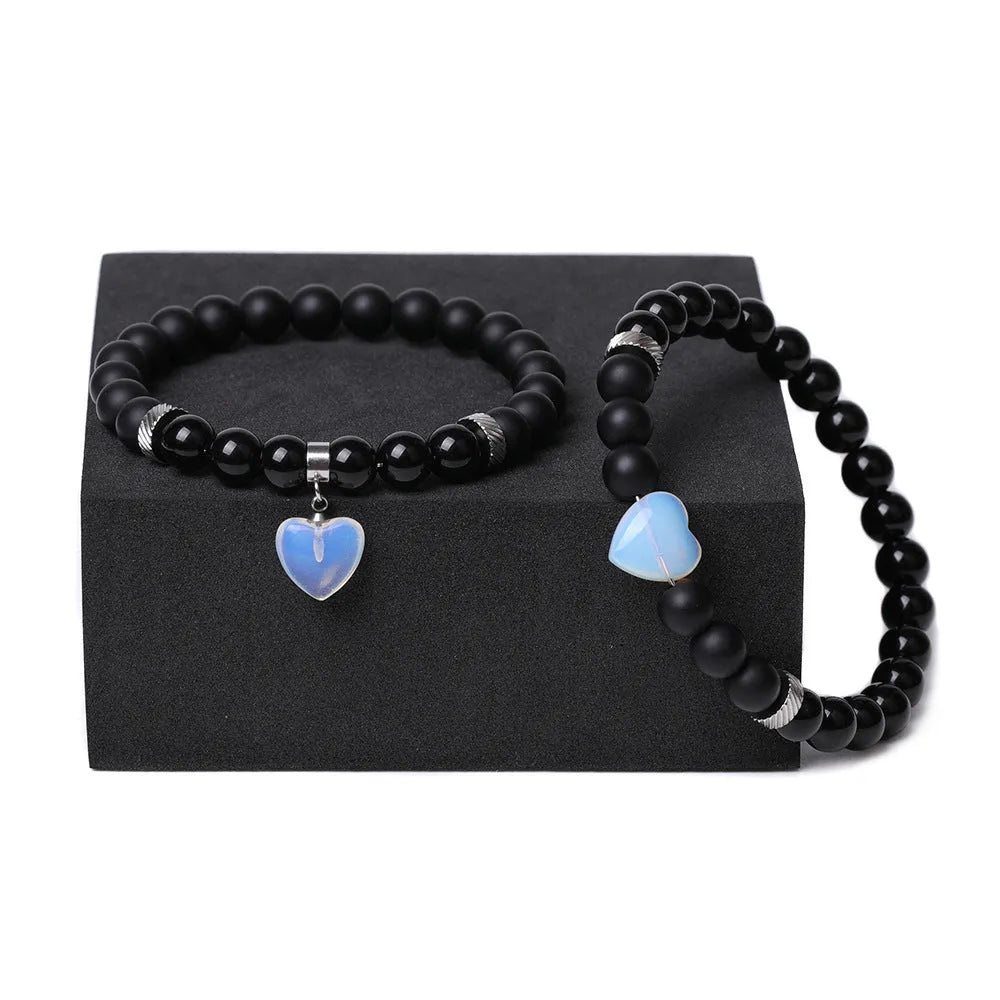 A pair of matching bracelets with polished geometric heart pendants made from natural stone.