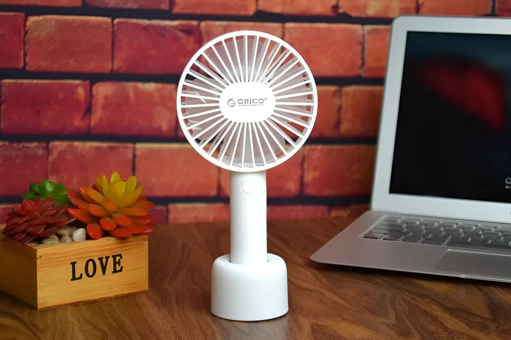 White ORICO FH1 handheld USB rechargeable desk fan with three-speed control on a desk.