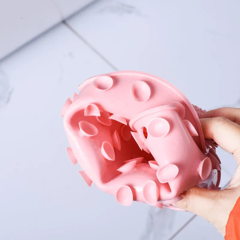 Orange TPR bath brush with silicone bristles and suction cups on base, shown on bathroom tiles.