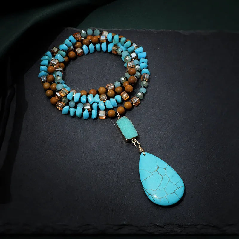 Close-up of a large turquoise blue heart-shaped water drop pendant necklace on a ball bead chain.