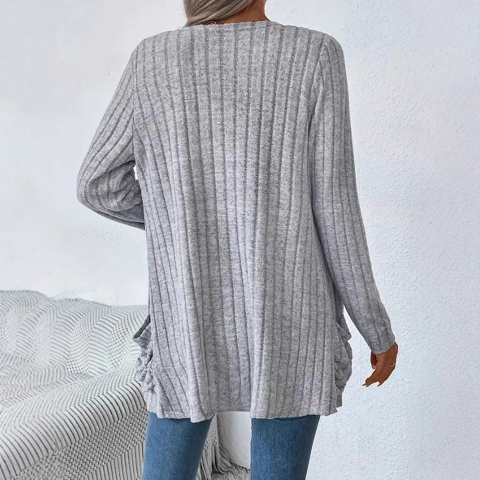 Plus size woman wearing a long sleeve grey cardigan with front pockets, loose fit.